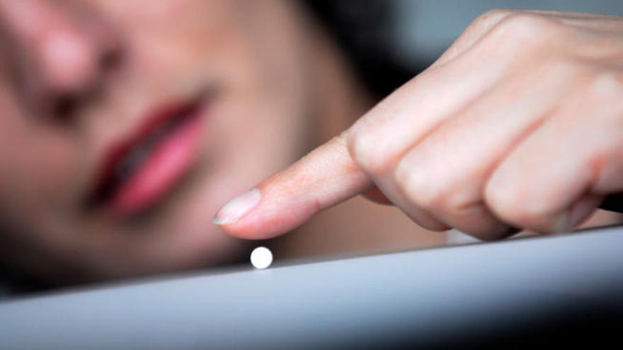 Una mujer juega con una pastilla antes de consumirla.