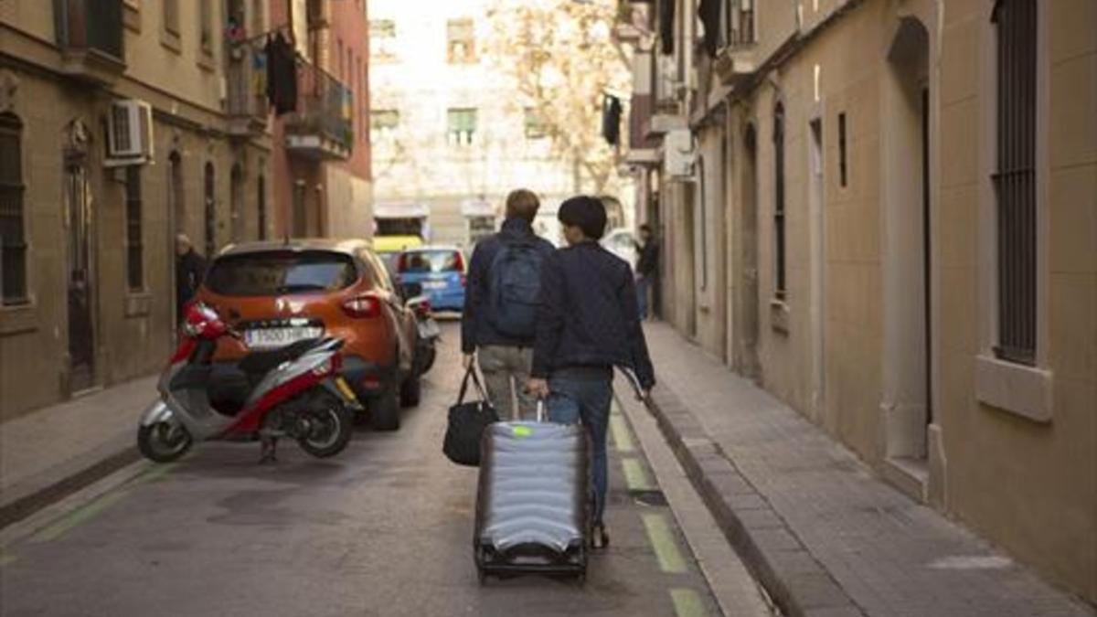 Dos turistas con su equipaje en una calle de la Barceloneta.