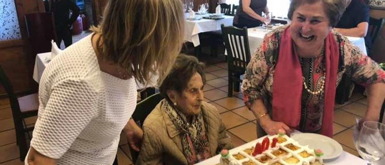 Lula Sánchez sopla las velas de su tarta de cumpleaños rodeada de su familia en una sidrería de Arriondas.