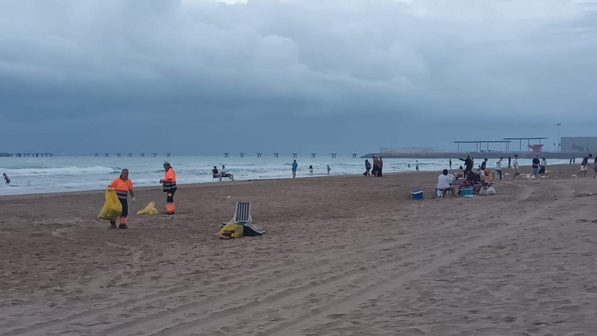 Los operarios ya trabajan en la playa del Port mientras algunos se resisten a terminar la fiesta.