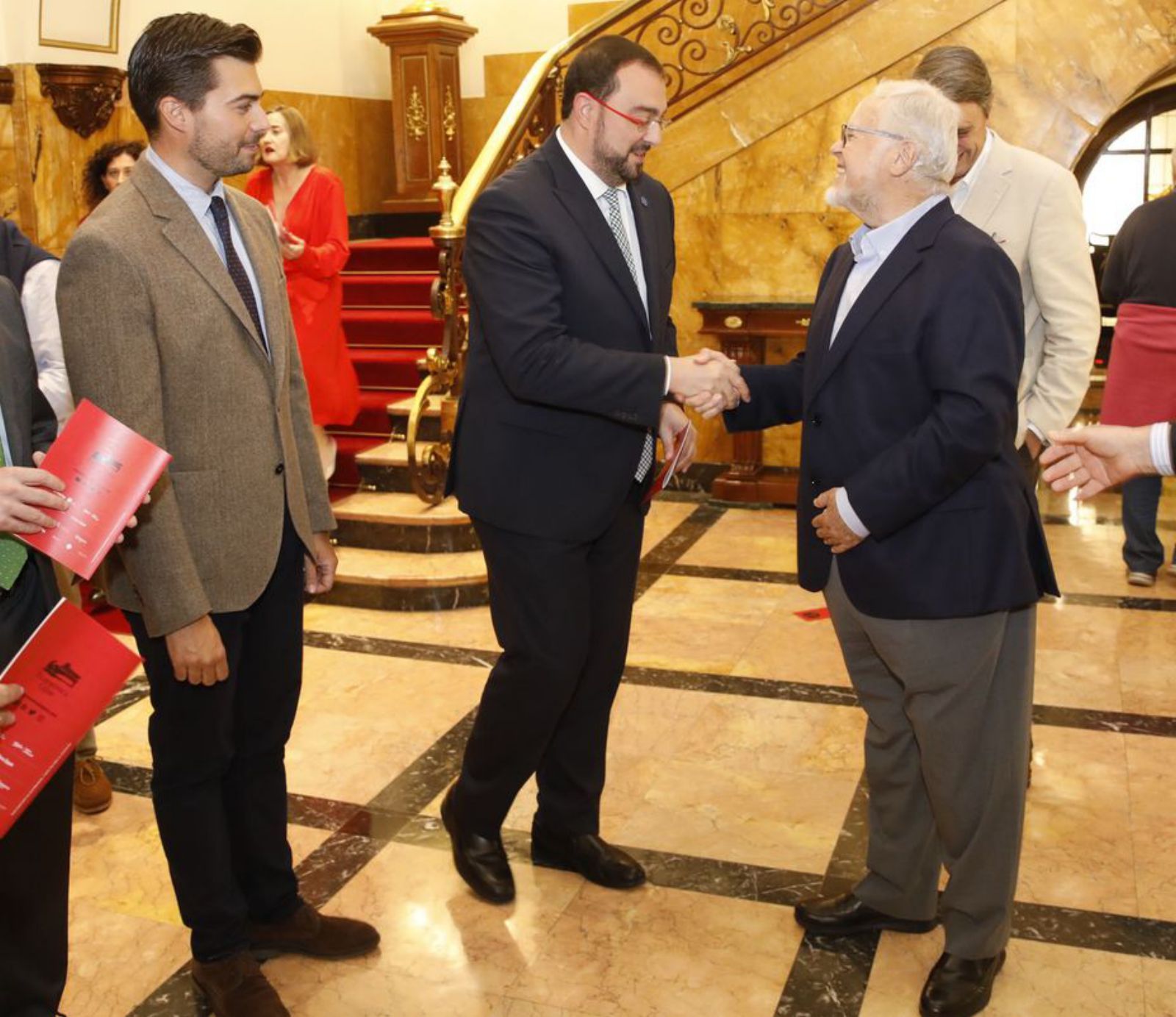 Por la izquierda, Antonio Hedrera, presidente de la Filarmónica, observa el saludo entre Adrián Barbón y Luis Vázquez del Fresno. | Á. González