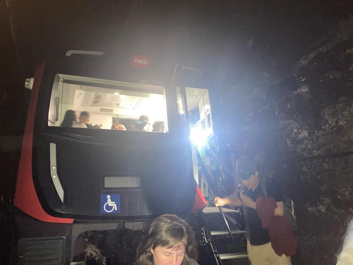 Pasajeros bajan de un convoy del metro de Barcelona y caminan por los túneles tras el apagón eléctrico