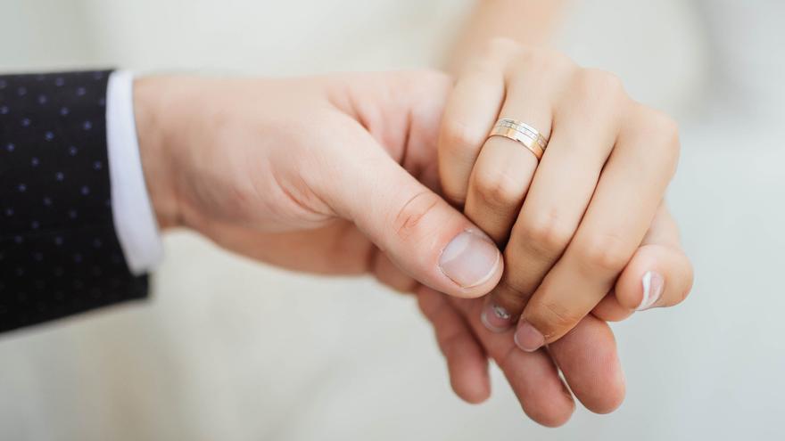 Una pareja cogida de la mano en su boda.