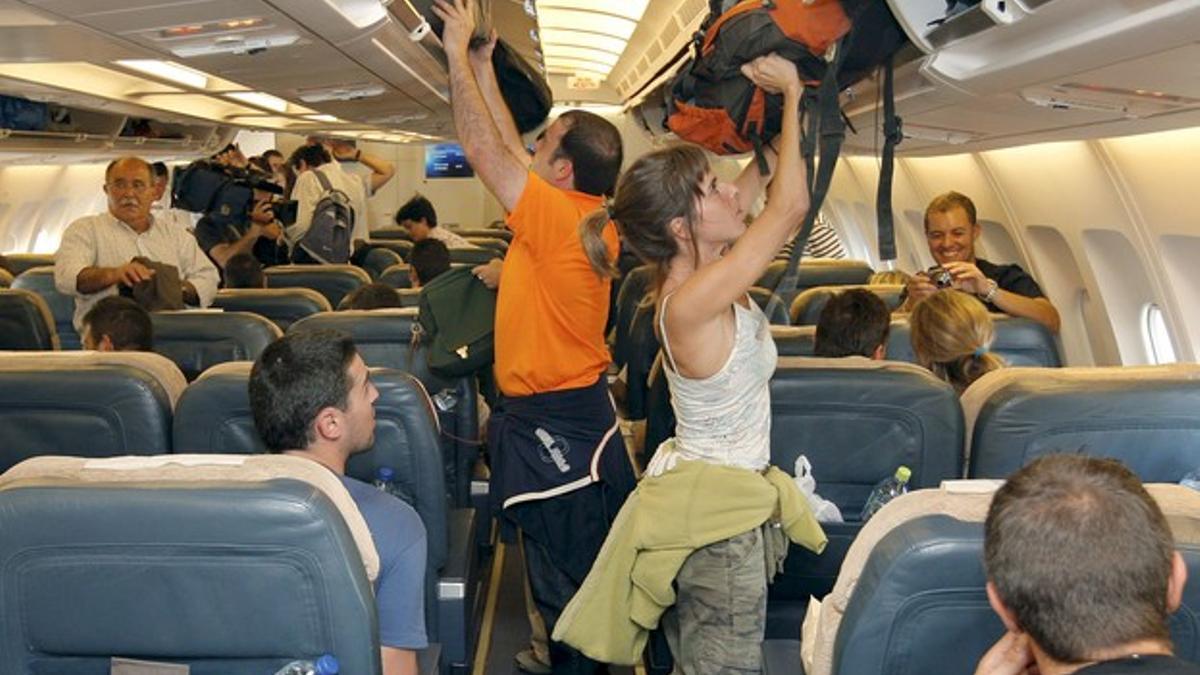 Turistas colocan su equipaje de mano en un avión.
