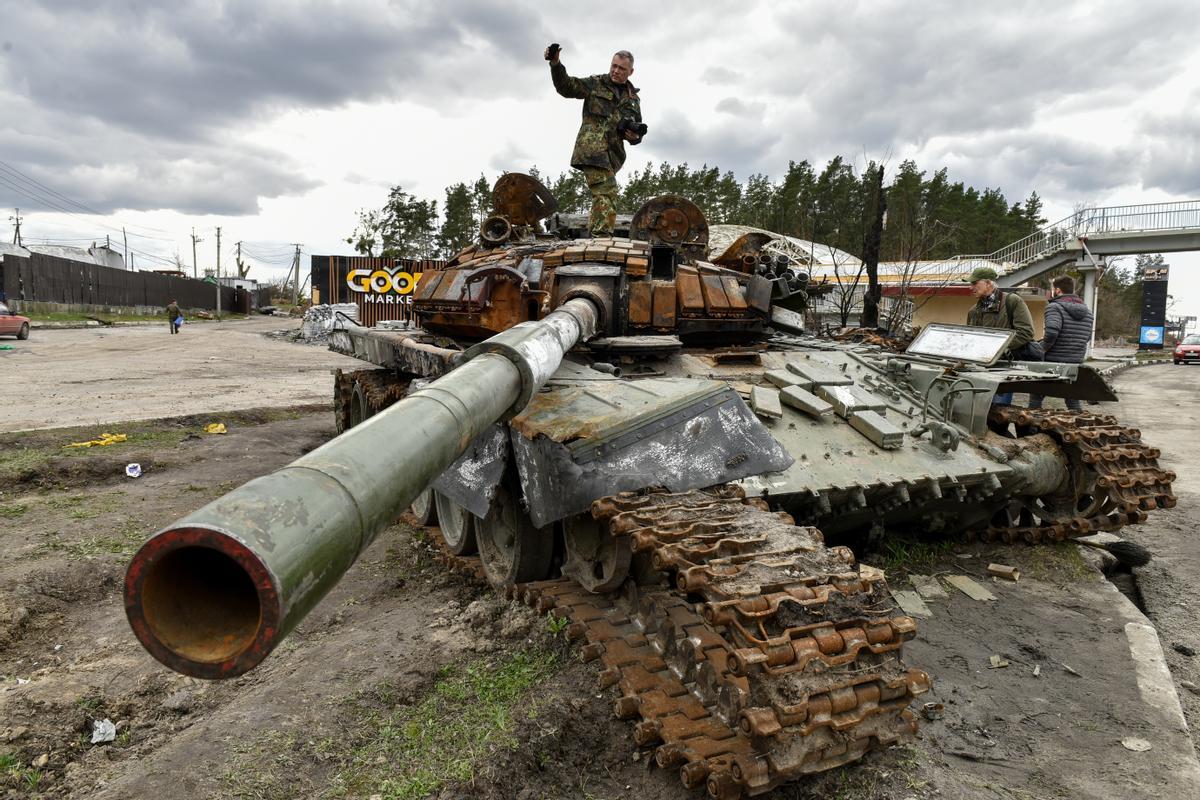 Un hombre se encuentra sobre tanques rusos destruidos en la aldea de Buzova del área de Kiev