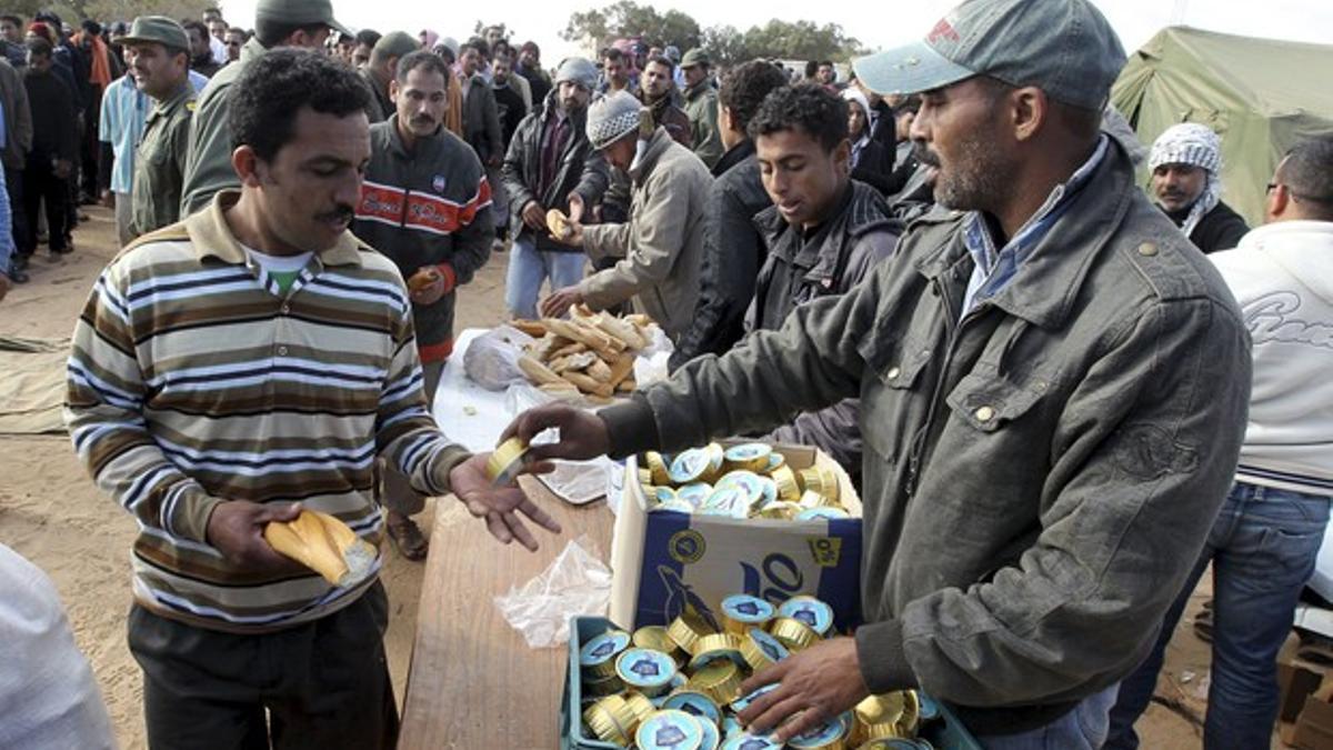 Ciudadanos egipcios que han huido de Libia hacen cola para recibir alimentos en un campamento cerca del paso de Ras Jedir, en la frontera libia con Túnez, este martes.
