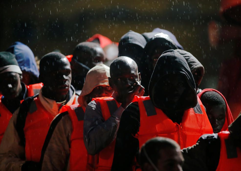 Migrants stand under the rain on a rescue boat ...