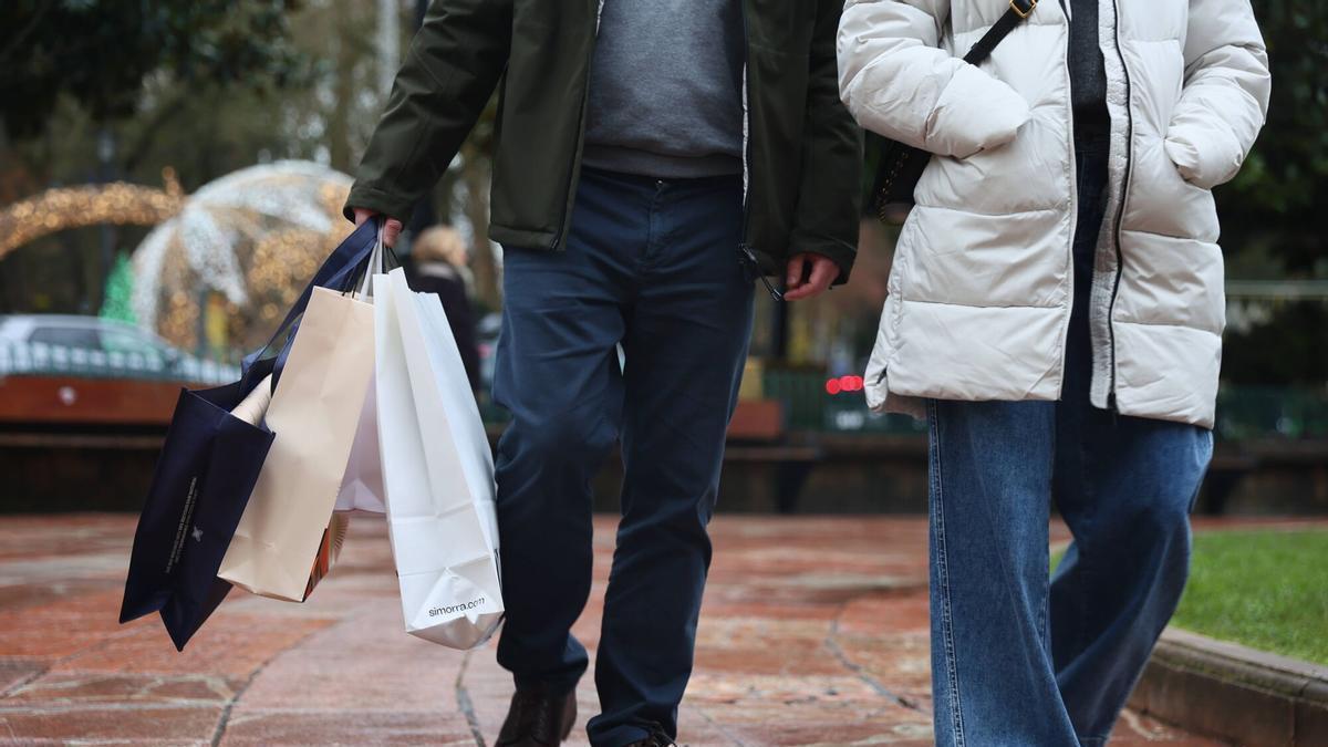 Un hombre carga con varias bolsas tras una jornada de compras.