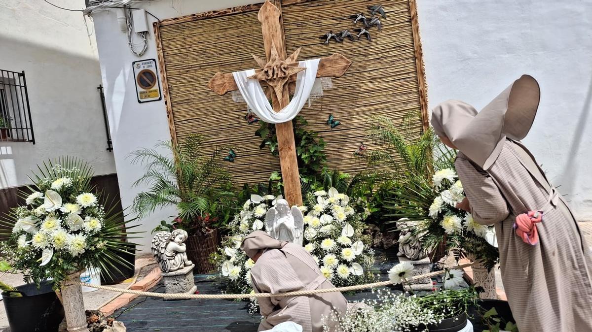 Dos monjas del santuario de la Plana ayudan a crear la cruz de flores de un mayoral