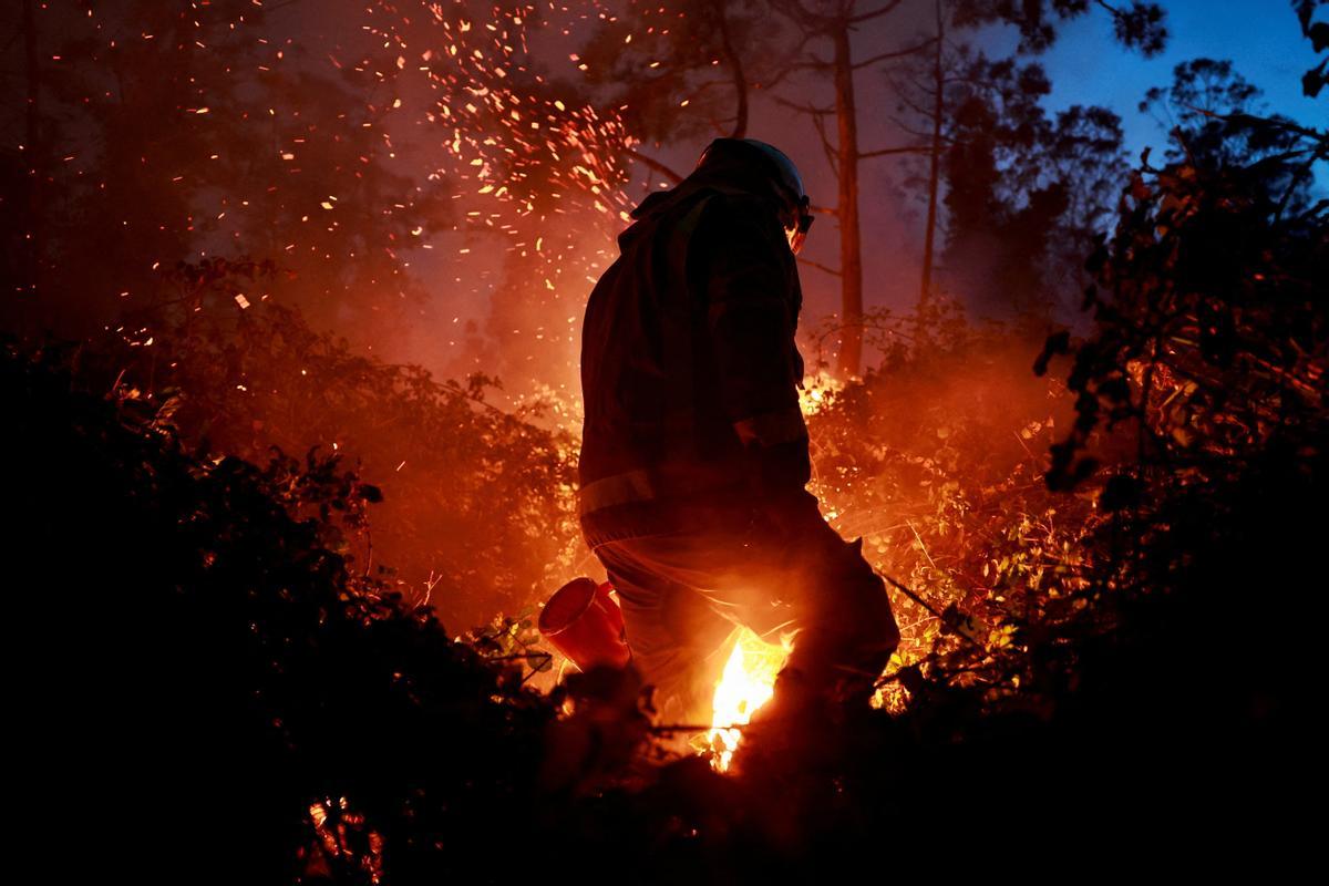 Un bombero gallego hace frente a las llamas en un bosque durante un brote de incendios forestales, en Piedrafita, Asturias