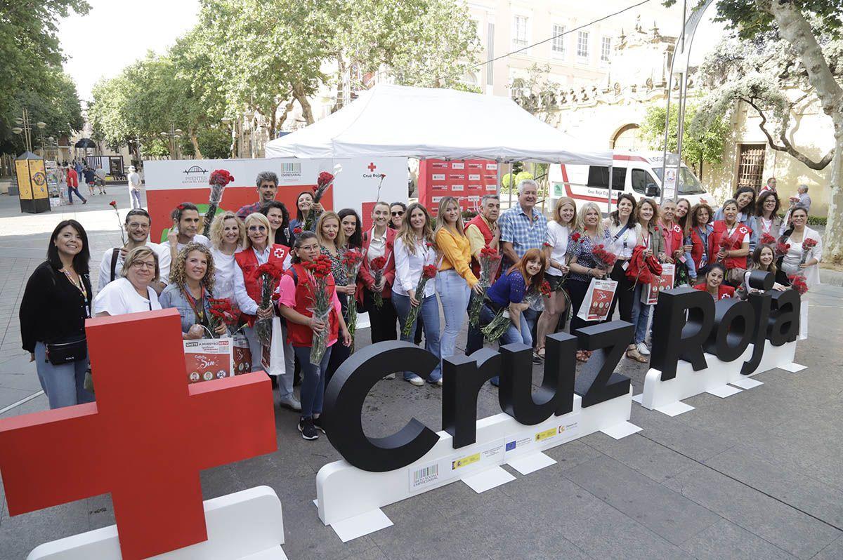 El personal de Cruz Roja posa con los claveles que repartirán a la espera de empezar la iniciativa