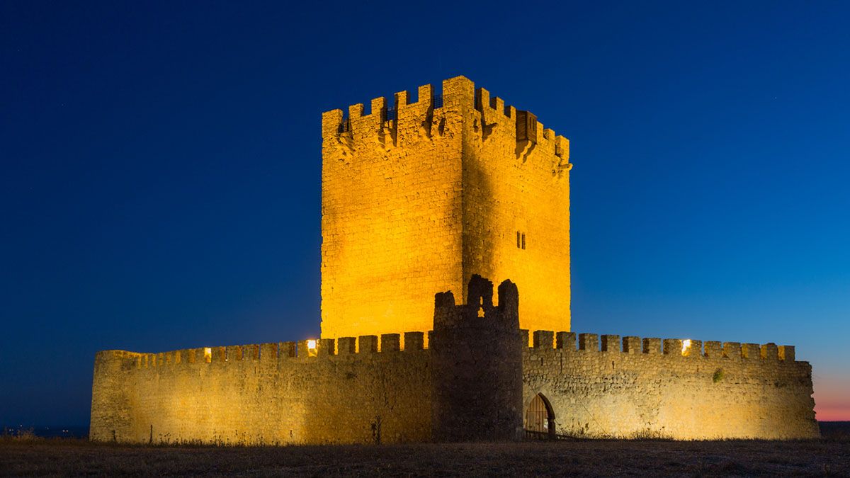 La torre del castillo, iluminada al caer la noche, se convierte en el gran faro histórico de este territorio mágico.