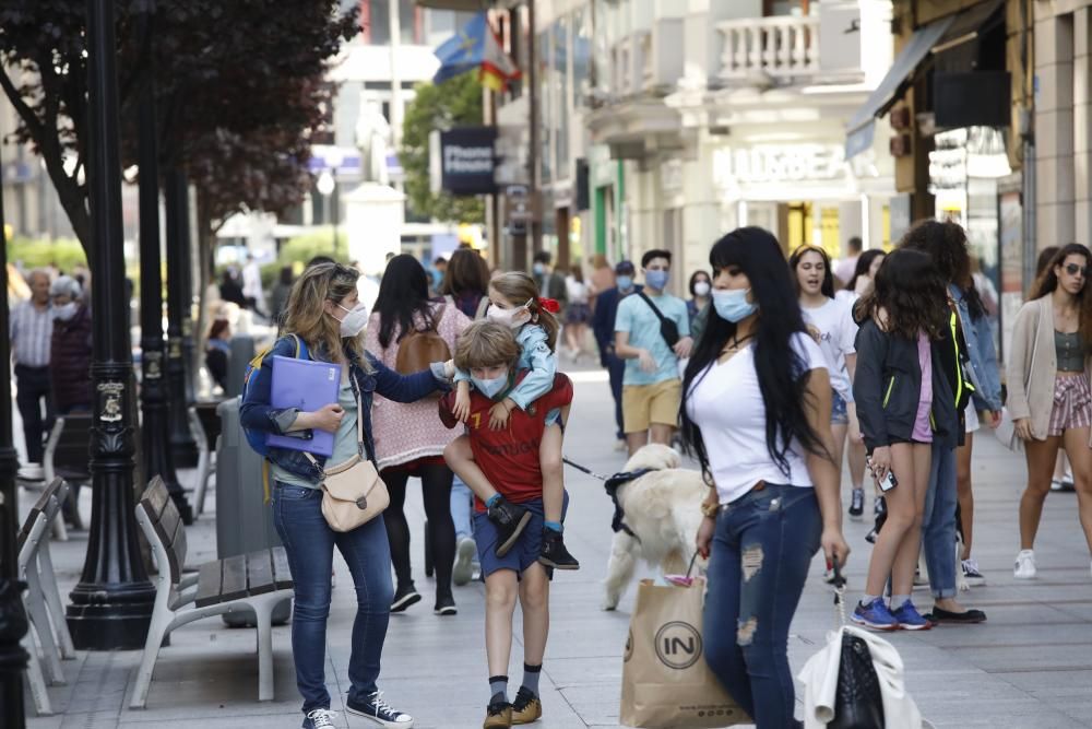 Gente con mascarilla y sin ella por el centro de Gijón.