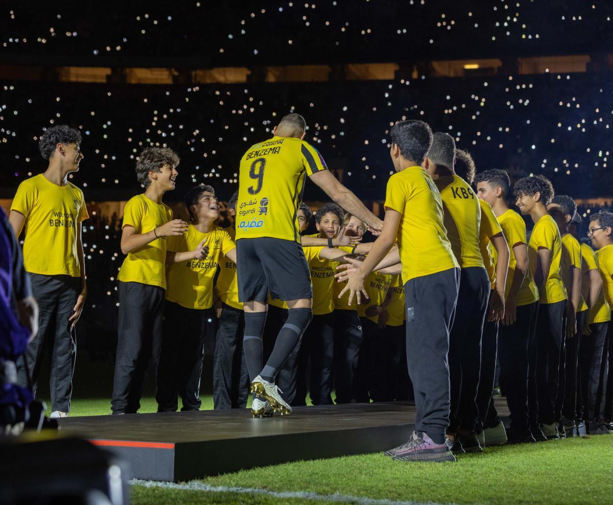 Un grupo de niños recibe a Karim Benzema en el césped del King Abdullah Sports City.