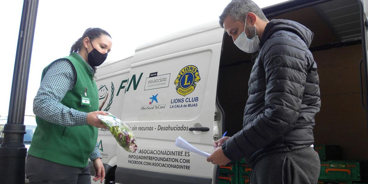 Una trabajadora de Mercadona entrega alimentos en Los Boliches a uno de los voluntarios del colectivo benéfico Adintre. | FRAN EXTREMERA