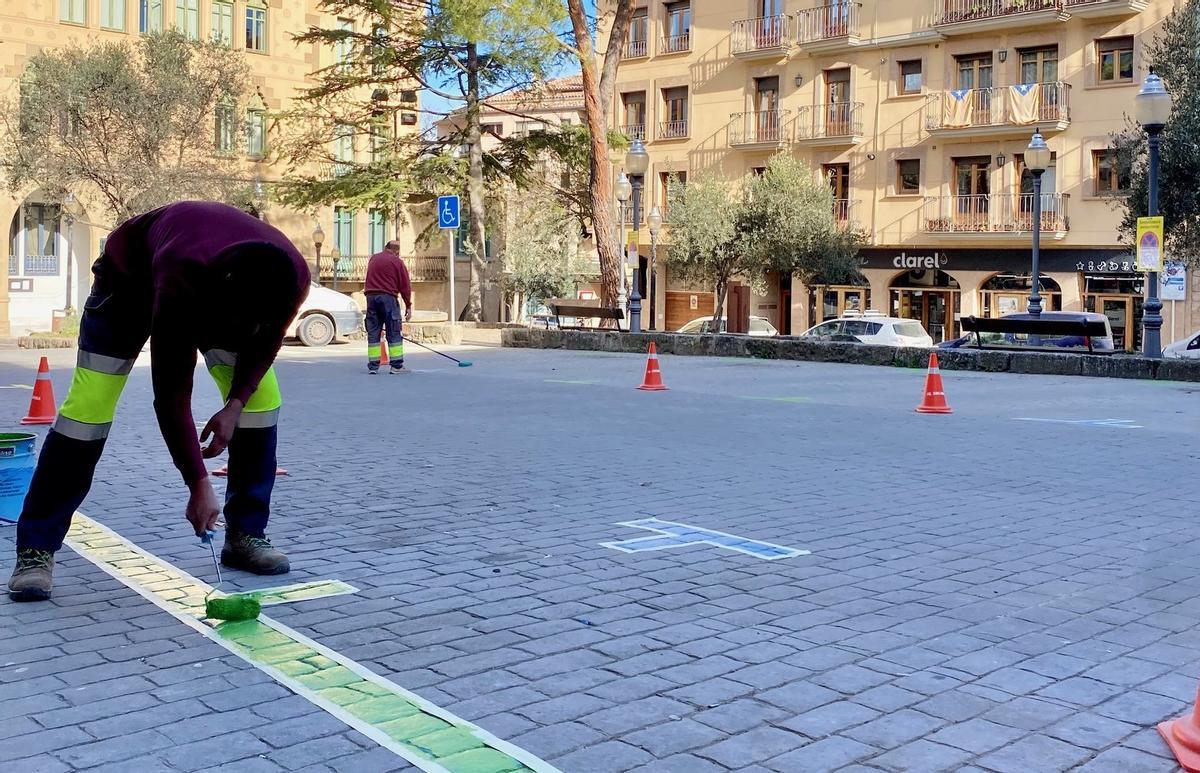 Un operari pinta la zona verda a la plaça Sant Roc