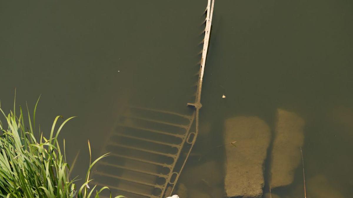 El bajo nivel del agua deja al descubierto restos de una barandilla caída al rio. 