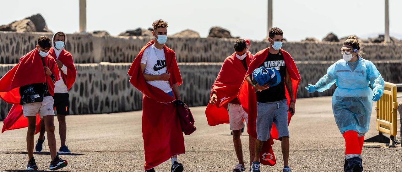 Una voluntaria de Cruz Roja atiende a dos migrantes en su llegada a Lanzarote.