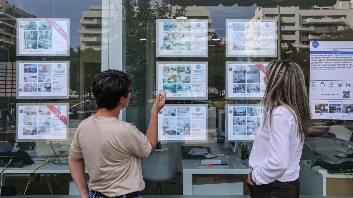 Dos posibles clientas miran las ofertas de una inmobiliaria en Alicante.