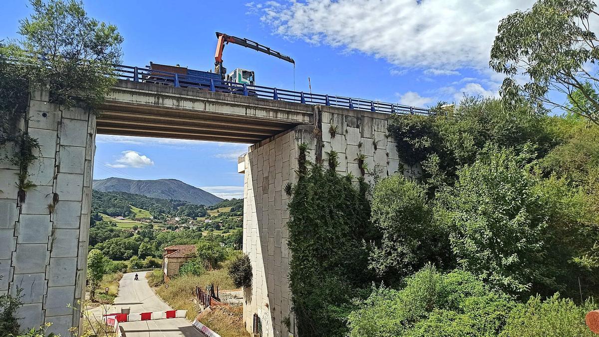 Operarios y maquinaria trabajan en el derribo del puente de la carretera N-634 entre Casazorrina y La Espina, en Salas. | S. Arias