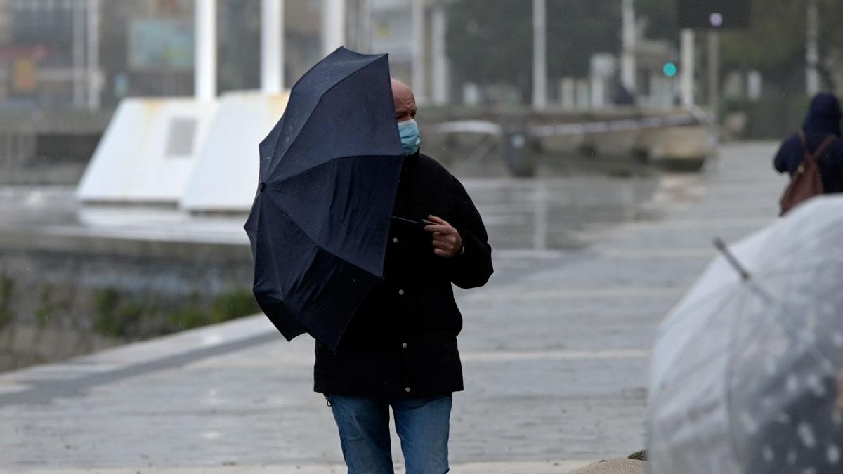 Un hombre se protege de la lluvia en A Coruña, en un día desapacible.