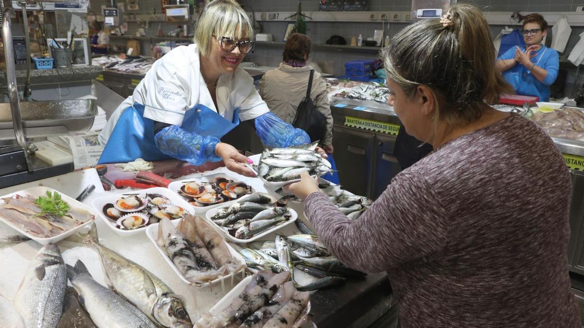 Una placera vende sardinas a una clienta en la plaza de Lugo.