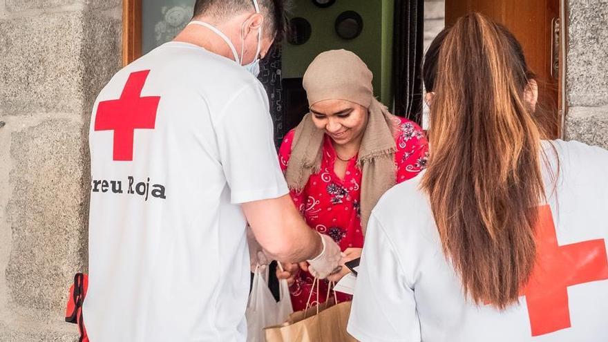 Dos voluntaris de la Creu Roja portant material de suport escolar