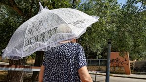 Una mujer se protege del sol con una pequeña sombrilla.