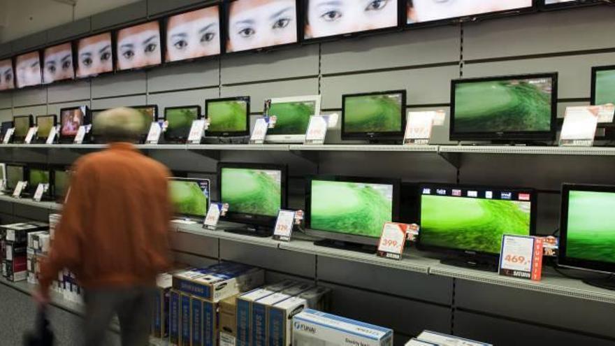 Un hombre observa los televisores en venta en un comercio.