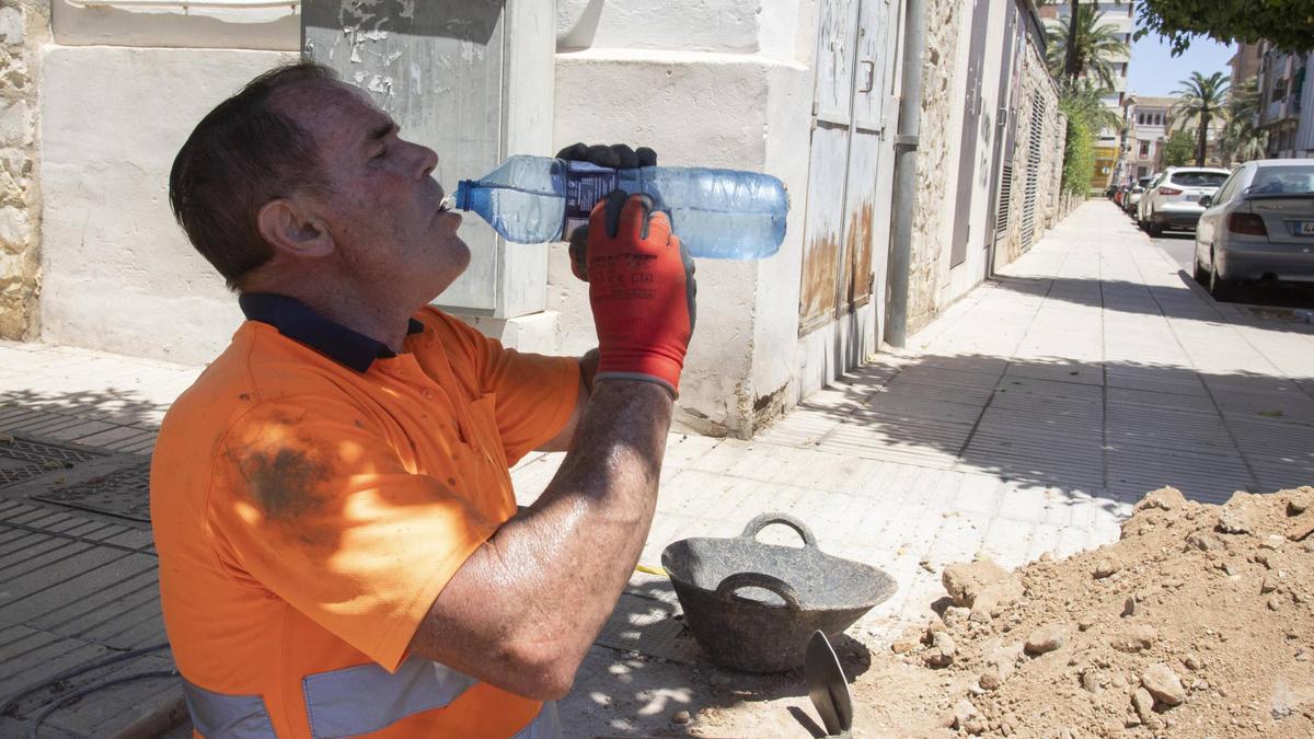 Un obrero bebe agua para protegerse del calor en Alzira.