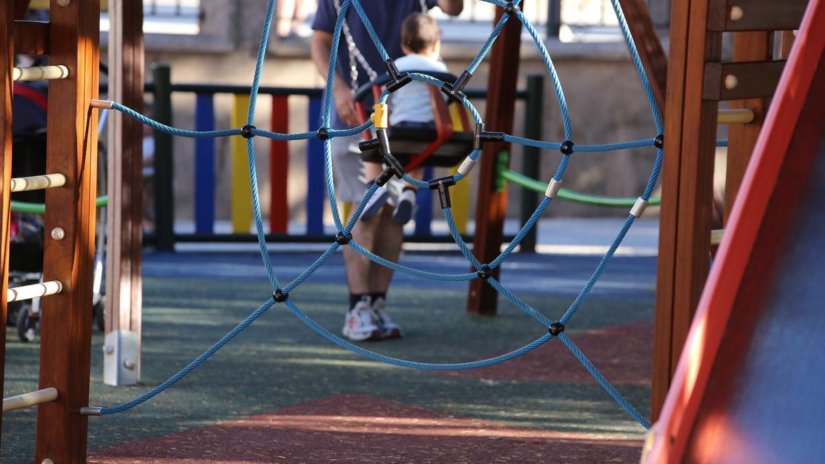 UN PADRE Y SU HIJO, EN UN COLUMPIO DE UN PARQUE INFANTIL.