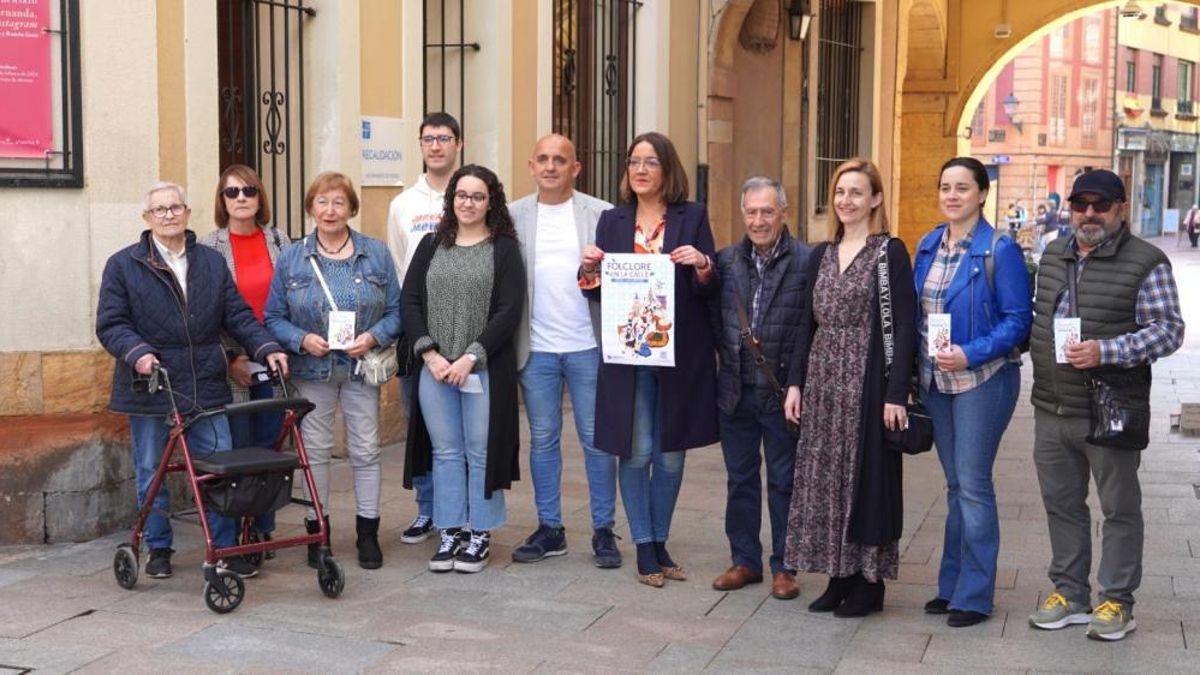 La edil Covadonga Díaz, con el cartel en el centro, junto a representantes de grupos folclóricos.