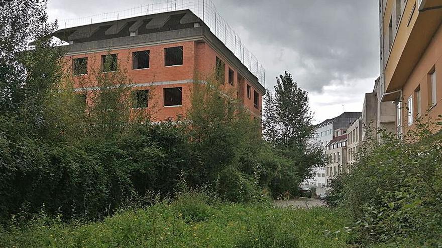 Edificio inacabado en la urbanización, rodeado de maleza.  |  // LOC