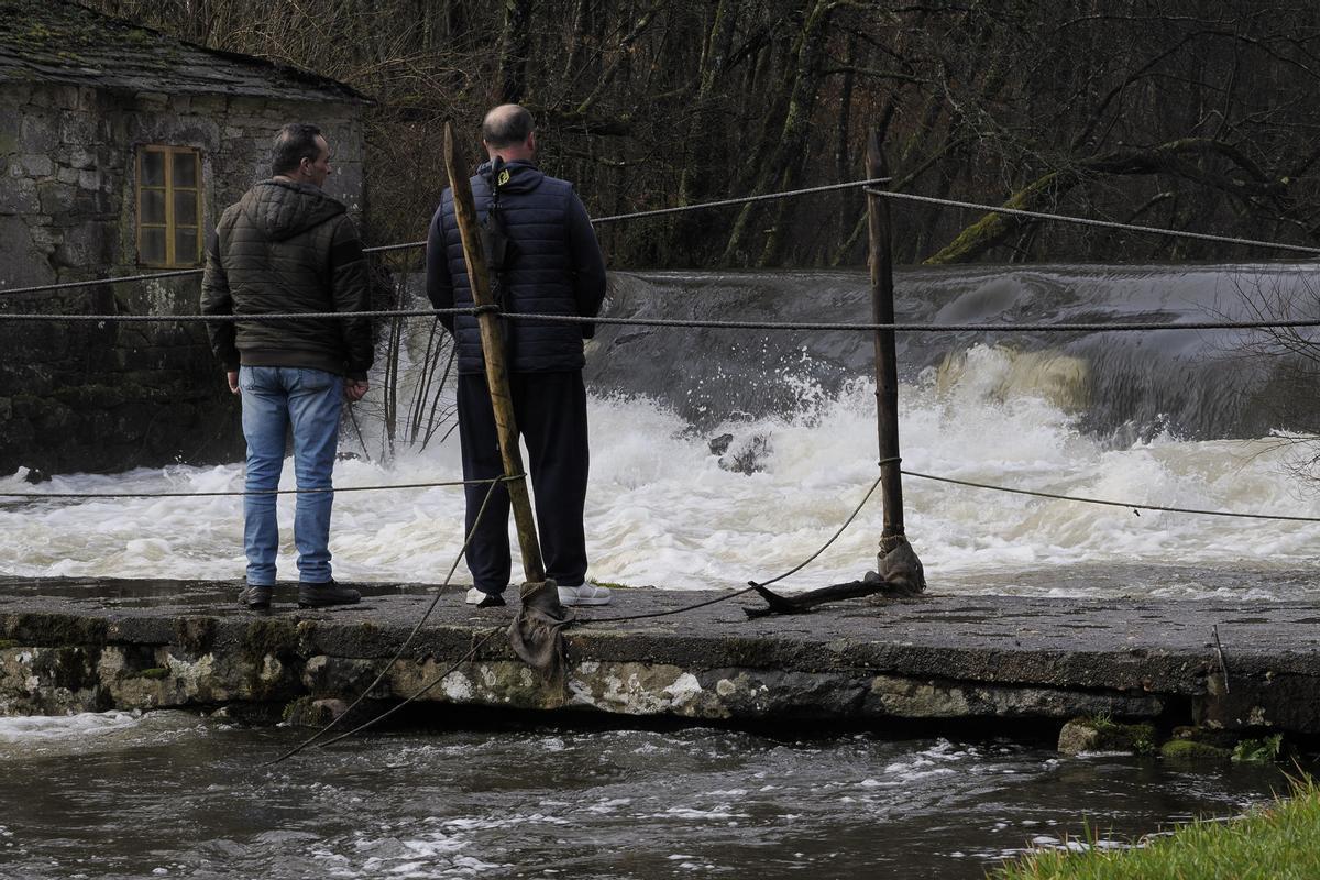 Dos hombres miran la crecida del Rio Narla a su paso por Friol, Lugo.
