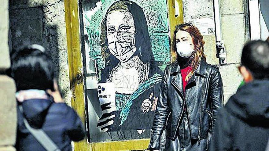 Una turista es fotografia al costat d&#039;un grafit de La Gioconda