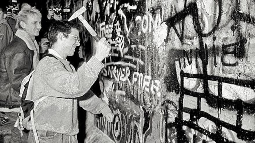 Un home mira de fer caure el mur de Berlín amb un martell