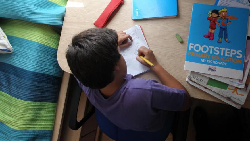 Un niño hace sus tareas escolares en su habitación.