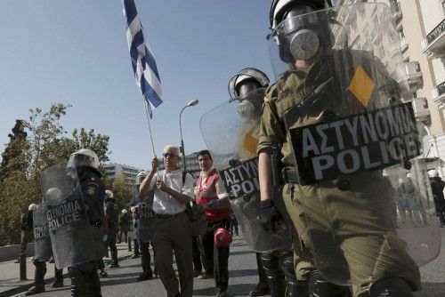 Man with Greek flag walks through line of Greek riot police at a protest march by Greece's Communist party in central Athens during a 24-hour labour strike