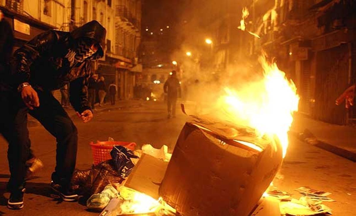 Joves encenen foc durant la nit als carrers d’Alger (Algèria), com a protesta per la pujada del cost de vida.