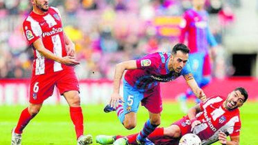 Busquets intenta llevarse el balón entre Koke y Luis Suárez. | EFE