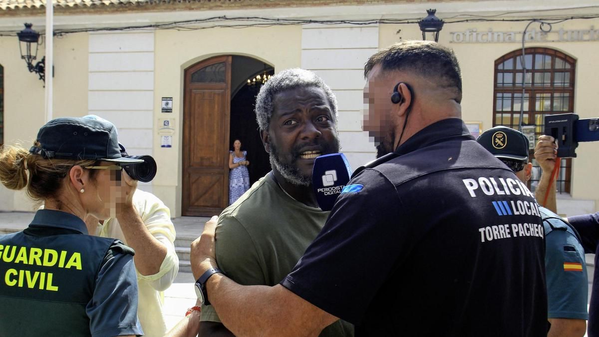 Un policía local intenta calmar al agitador Bertrand Ndongo tras un encontronazo con Podemos.