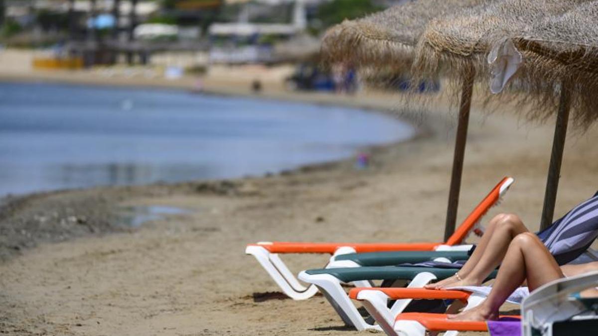 Dos personas descansan en sendas tumbonas en una playa de La Manga, este verano.  | IVÁN URQUÍZAR
