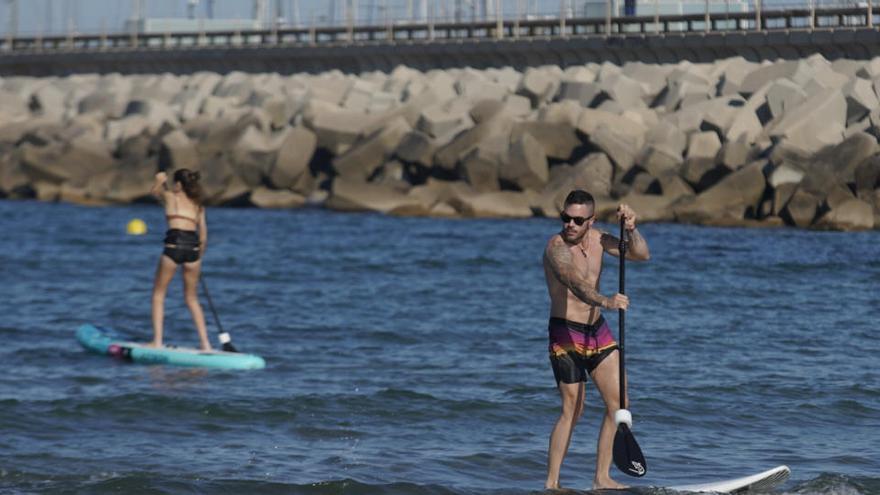 Dos personas hacen paddle surf en la playa de Las Arenas