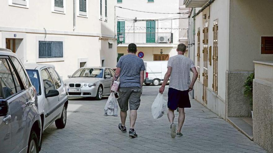 Dos turistas salen de un supermercado de Búger con la compra.