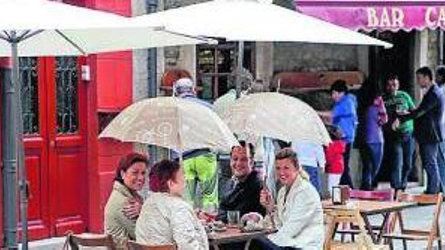 Turistas sentados en una terraza con paraguas y sombrilla.