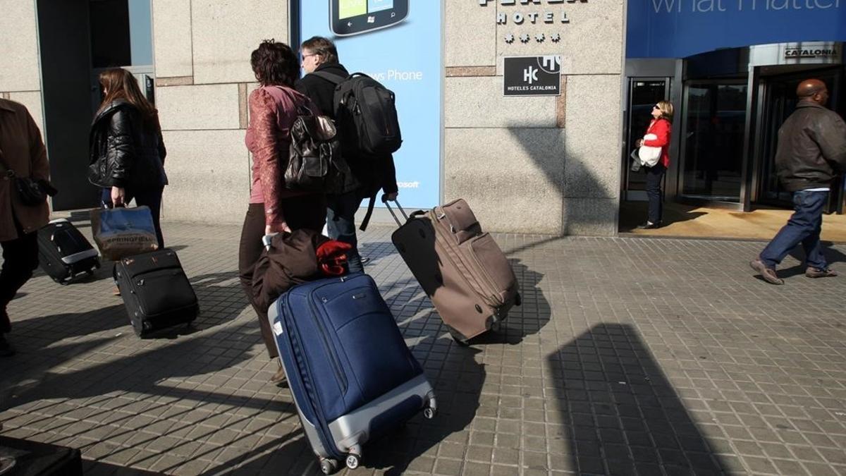 Turistas con la chaqueta sobre la maleta el último fin de semana de febrero en Barcelona.
