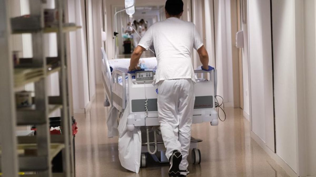 Un celador trasladando a un paciente en un hospital público.