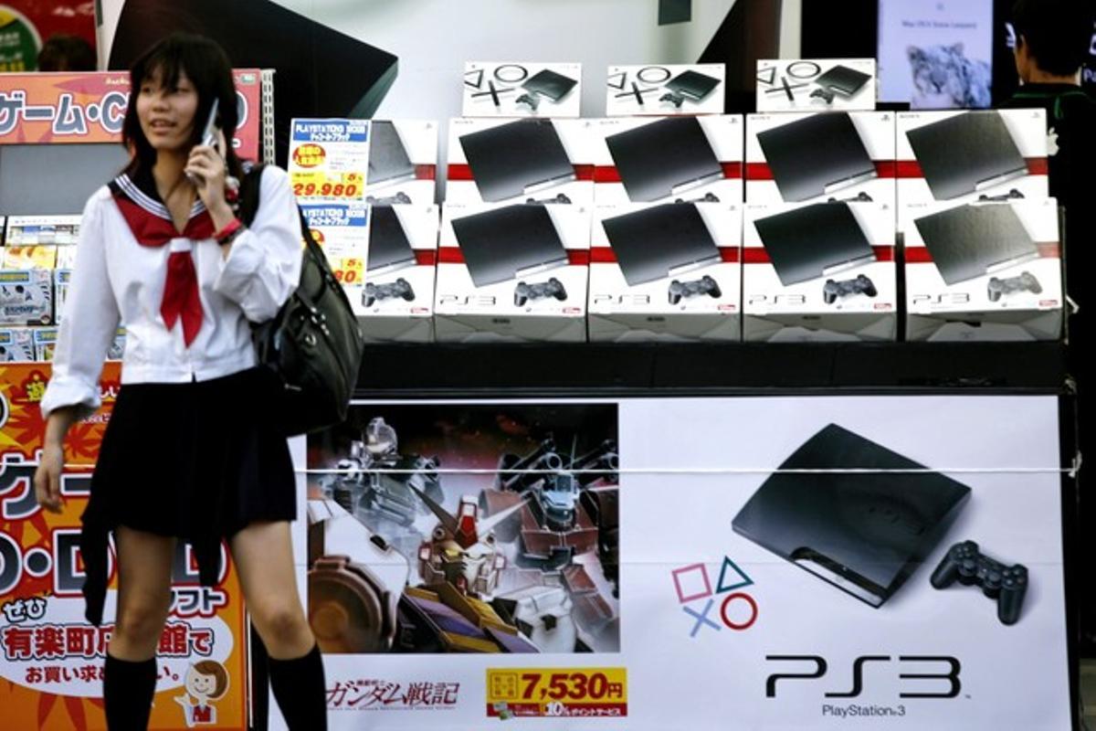 Una estudiant japonesa parla per telèfon mòbil davant de diverses consoles PlayStation 3.