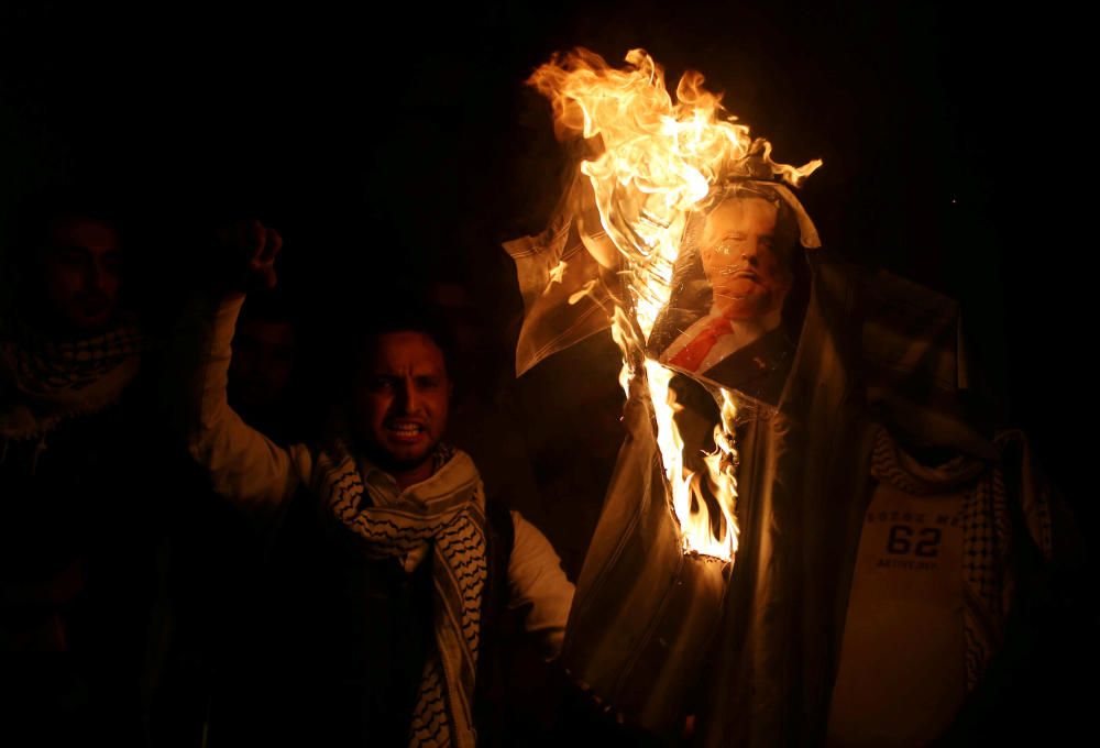 Palestinians burn a poster depicting U.S. ...