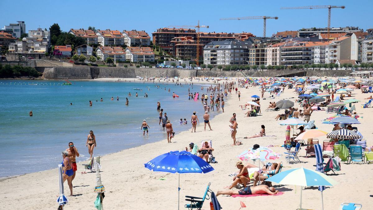 La playa de Silgar, en Sanxenxo, con los edificios residenciales en primera línea de fondo durante el arranque de la temporada de verano.